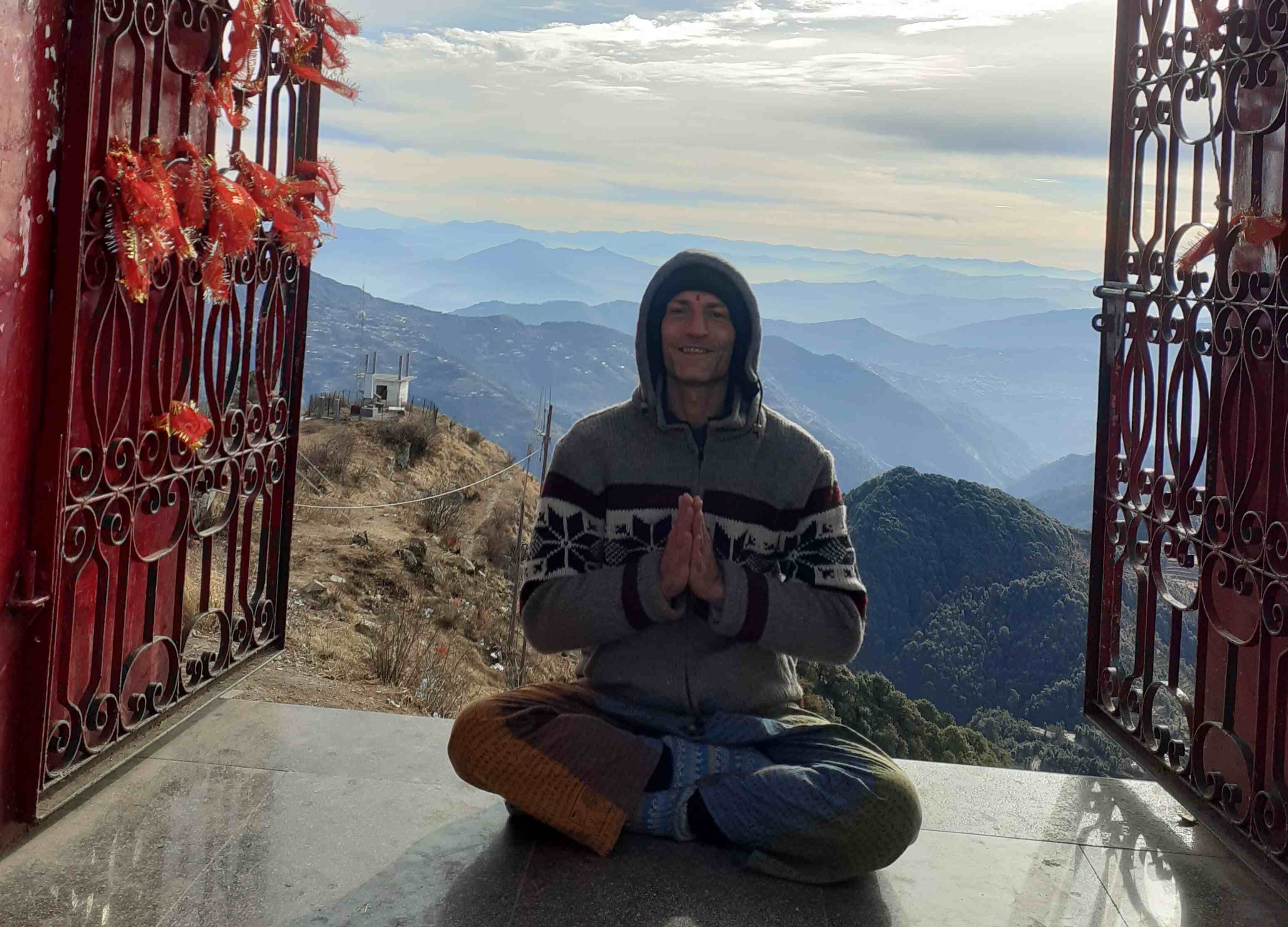 Nils Kriedner sitzt im Himalaya meditierend mit den Händen in Namaste